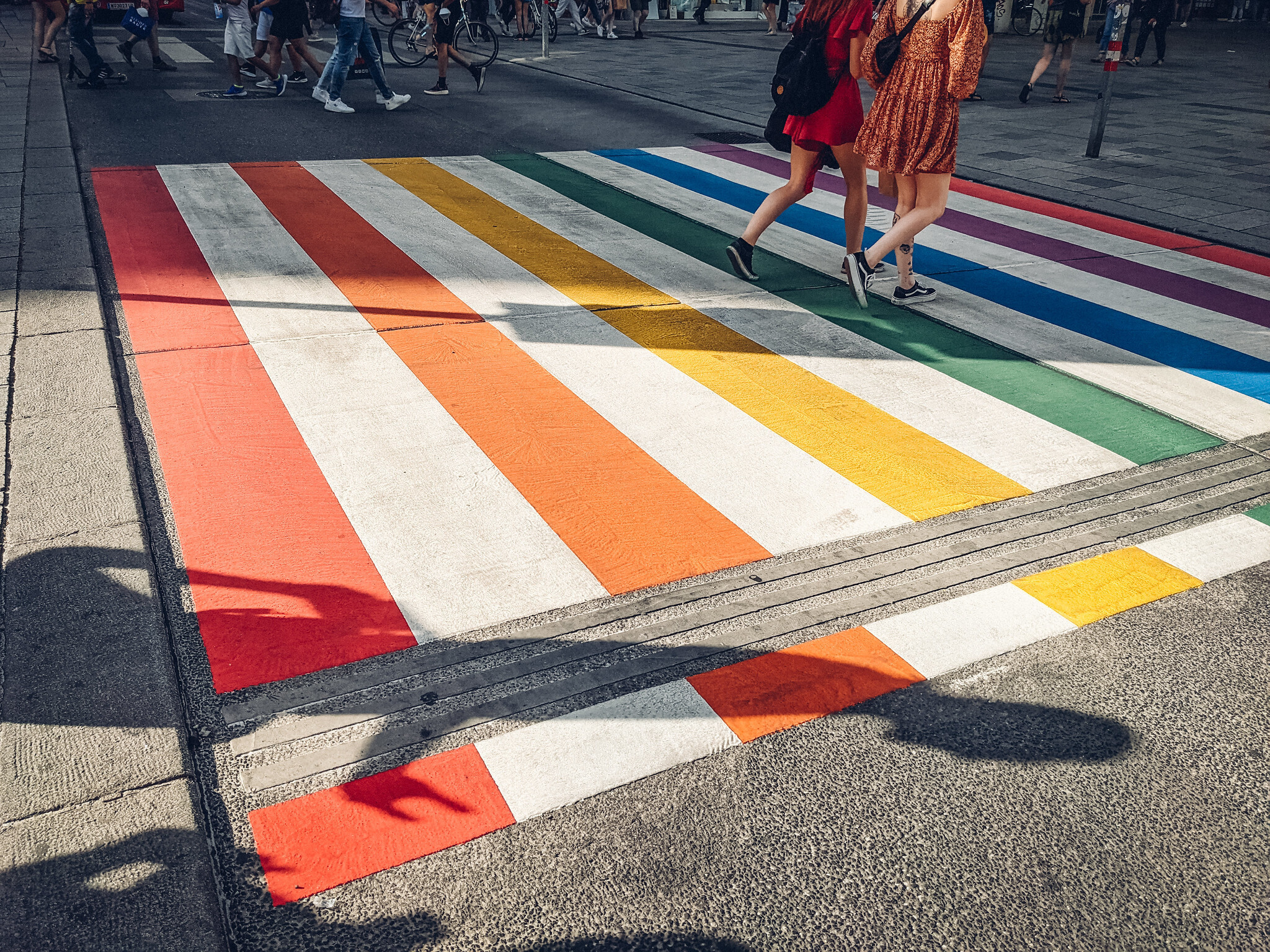 Zwei Frauen laufen über einen Zebrastreifen in Regenbogenfarben