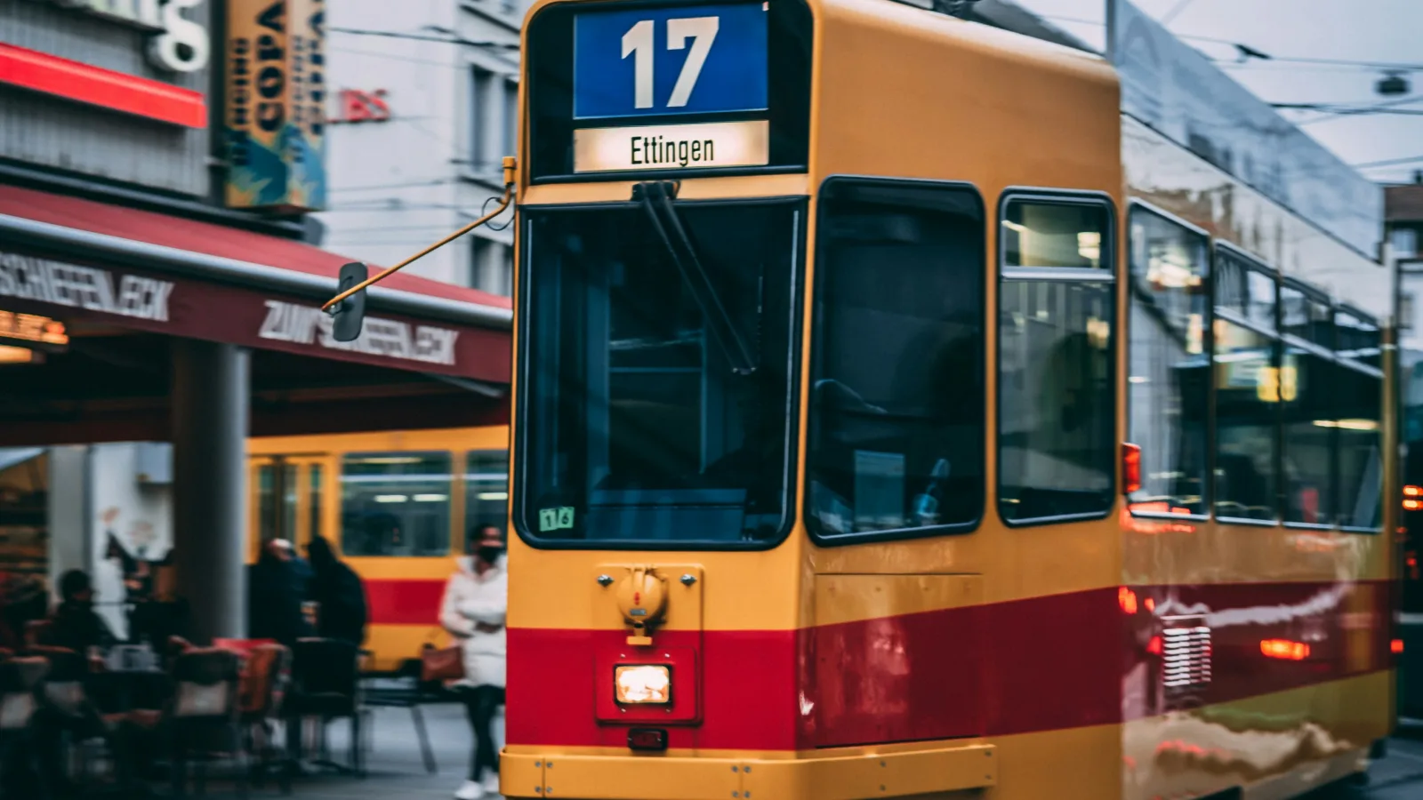 Ein gelbes Tram mit rotem Streifen und der weissen Liniennummer 17 auf blauem Grund fährt durch die Innenstadt von Basel.