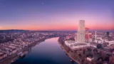 Panoramablick auf Basel nach Sonnenuntergang. Im Vordergrund sind der Rhein und die Roche-Türme zu sehen.