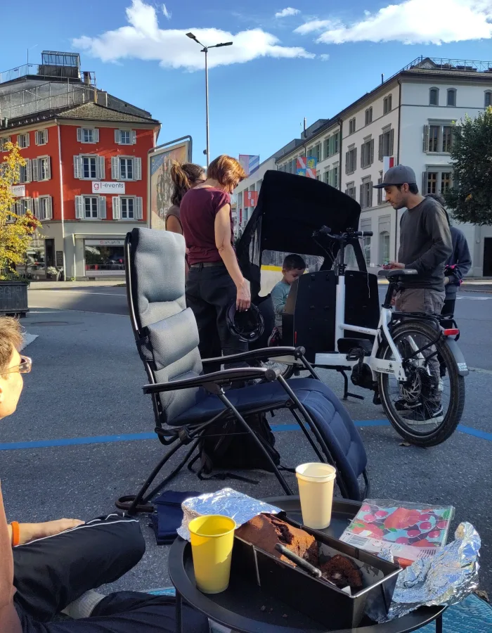 Ein sehr junger Besucher ist in das Lastenrad eingestiegen und scheint freude daran zu haben. Im Vordergrund: Getränke und Kuchen auf dem Tisch