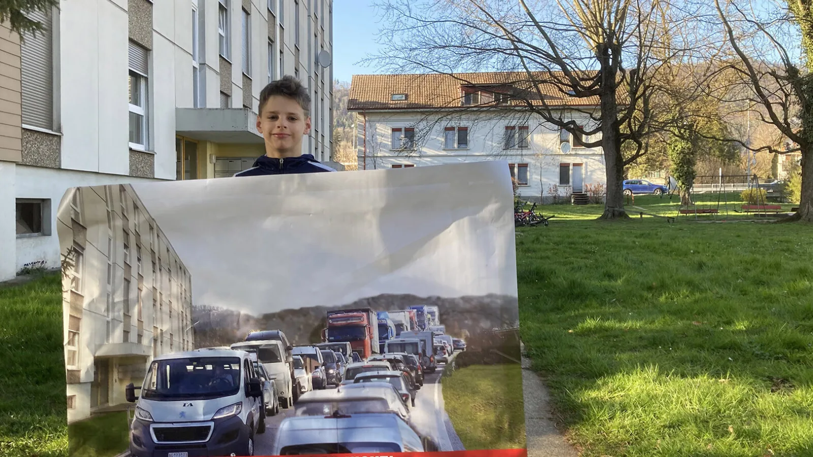Kind steht im Quartier mit einem Plakat gegen die Umfahrung Klus