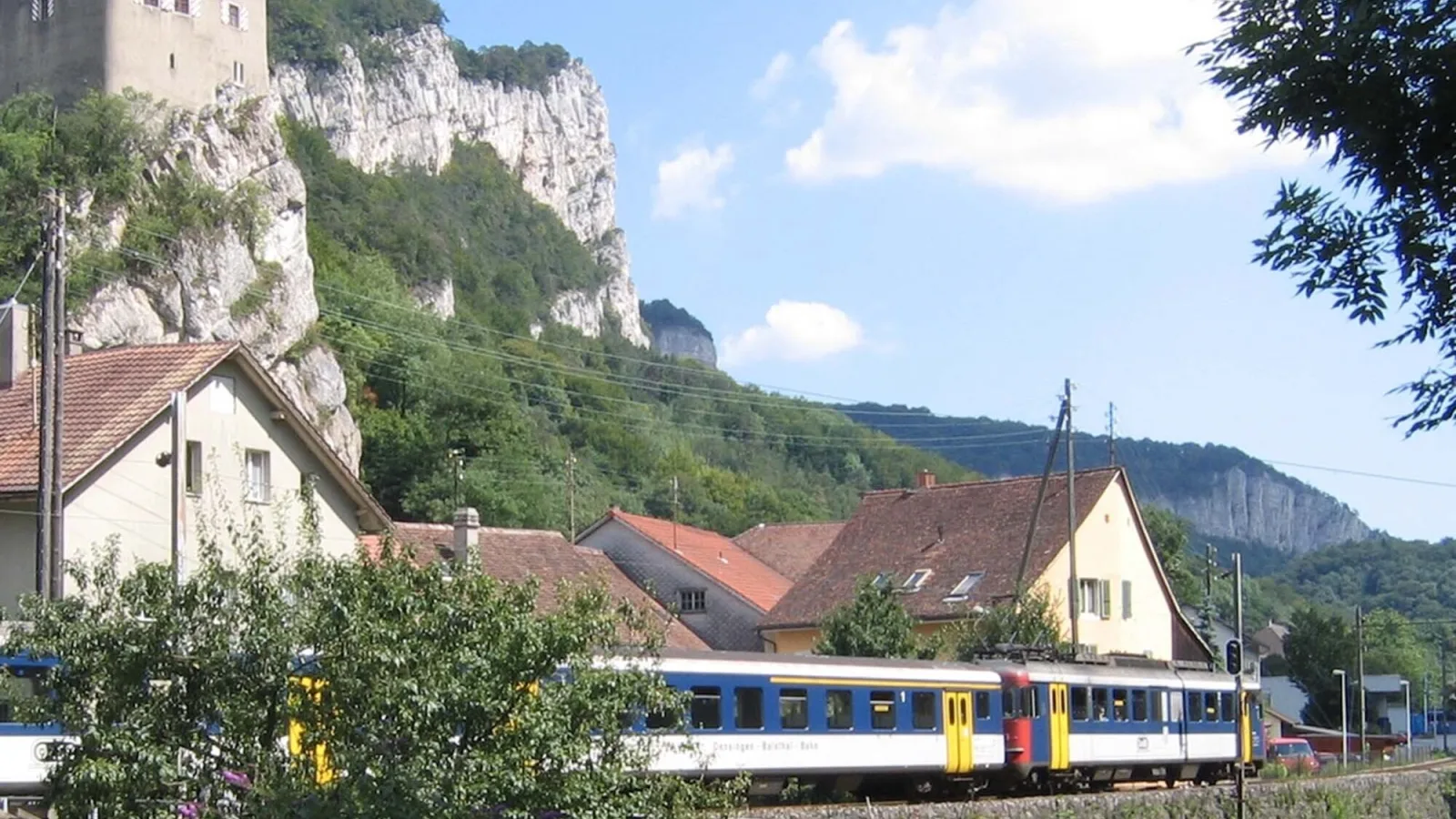Zug fährt an einem See vor einer Burg vorbei