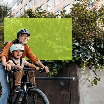 Frau auf Velo mit Kind in Kindersitz